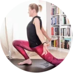 Kobieta ćwiczy jogę w pomieszczeniu, wykonując pozycję do wykroku na macie. Ma na sobie czarny top i różowe legginsy, a w tle półkę wypełnioną książkami i światło słoneczne wpadające przez okno.