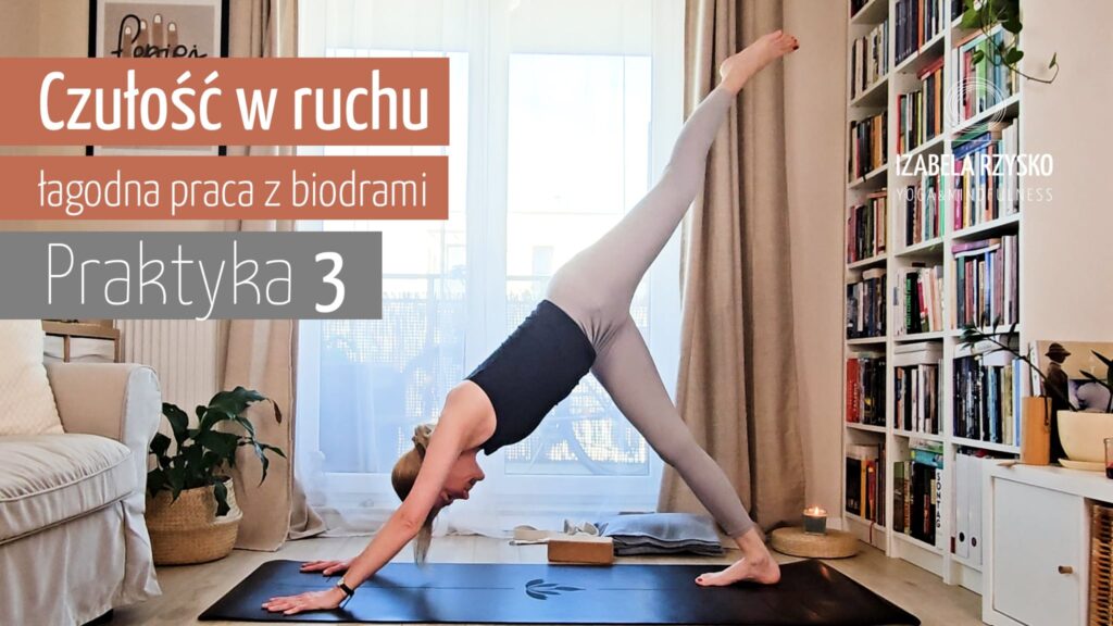 Kobieta ćwiczy joga online w pomieszczeniu, wykonując pozycję psa z trzema nogami w dół na czarnej macie. Znajduje się w jasnym pokoju z półkami na książki, beżową kanapą, roślinami, neutralnym wystrojem i polskim tekstem nałożonym na obraz.