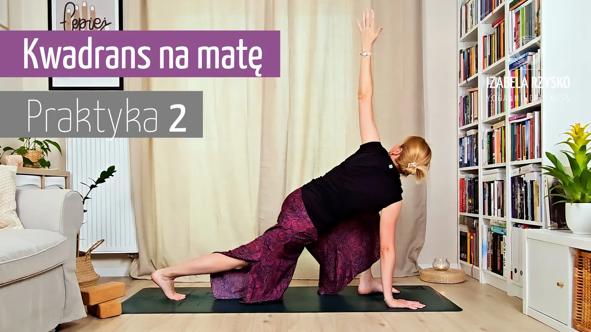 Iza Rzysko ćwiczy jogę online na macie w domu, unosząc lewą rękę do góry w pozycji skrętu z wykrokiem. Na ekranie widnieje napis „Kwadrans na macie – Praktyka 2”. W przytulnym pokoju widać regały z książkami i białe krzesło.